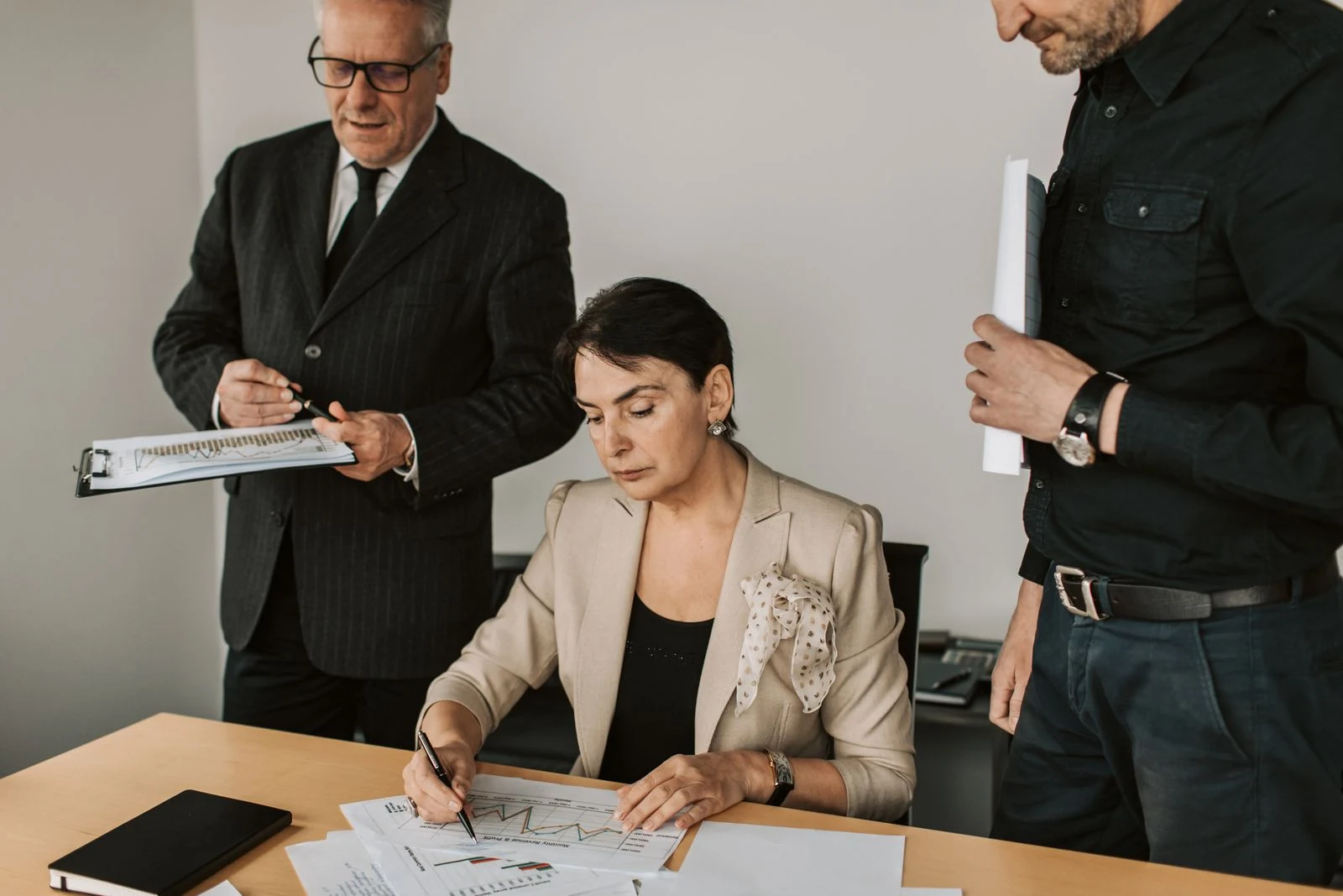 Business professionals examine financial reports together in an office.