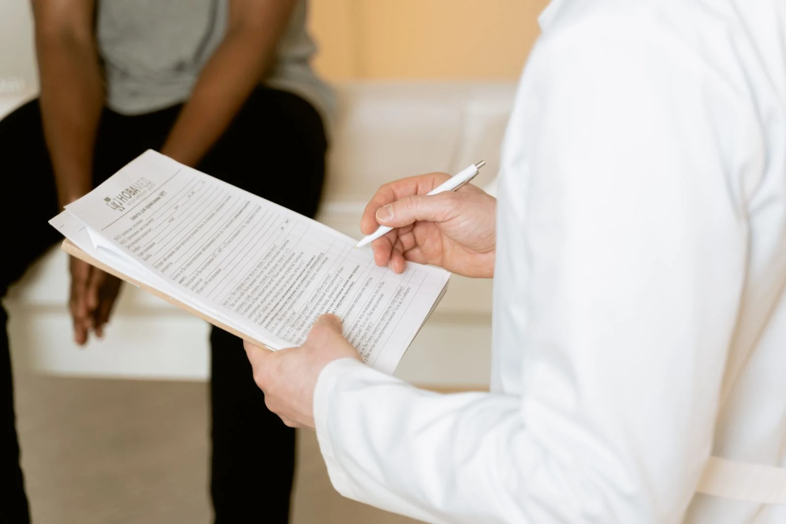 A clinician reviews medical paperwork during a patient consultation.