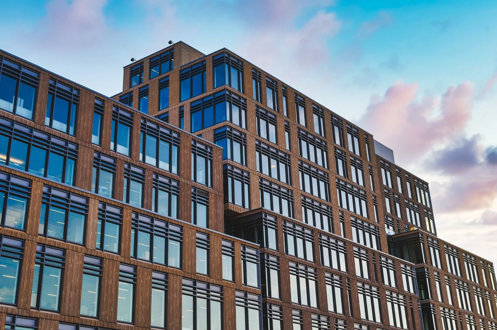 A contemporary commercial building with warm wood cladding and reflective glass windows.