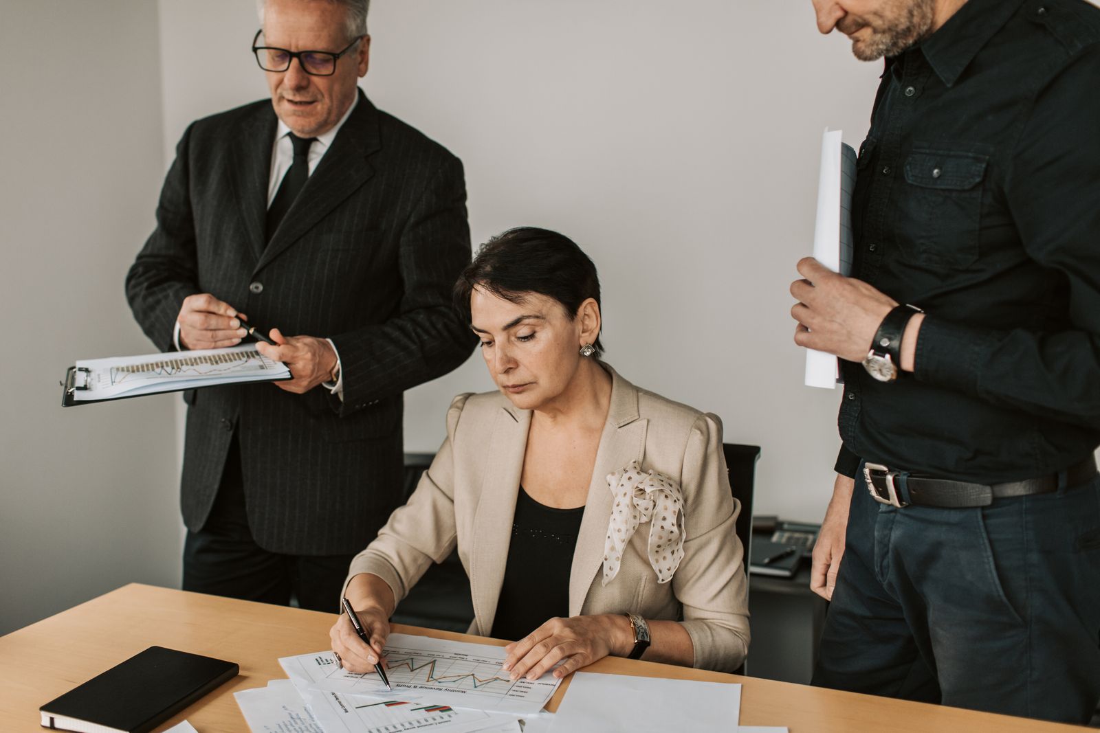 Business professionals examine financial reports together in an office.