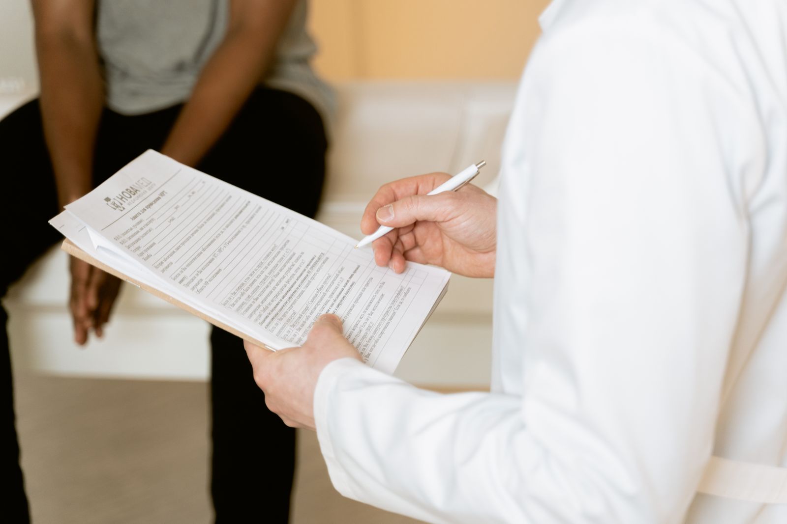 A clinician reviews medical paperwork during a patient consultation.
